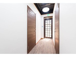 Un pasillo con puertas de madera y un ventanal al final.