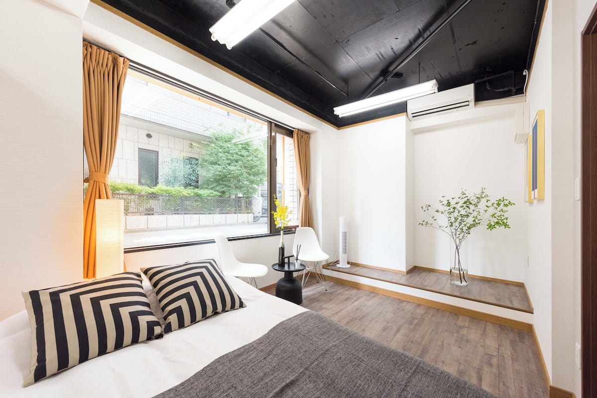 Ein Hotelzimmer mit einem Bett, zwei Stühlen, einem kleinen Tisch, einem Spiegel und einer Topfpflanze.