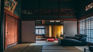 A traditional Japanese room with tatami flooring, a low table, a sofa, and sliding doors leading to another room. - Maruki Saifuku (Kakuda)