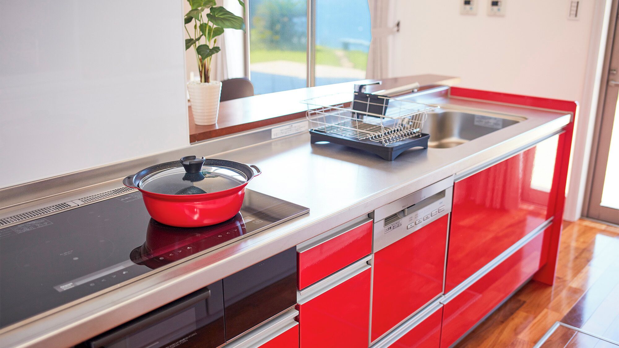 A modern kitchen with a red and black color scheme, a built-in stove, and a dishwasher.
