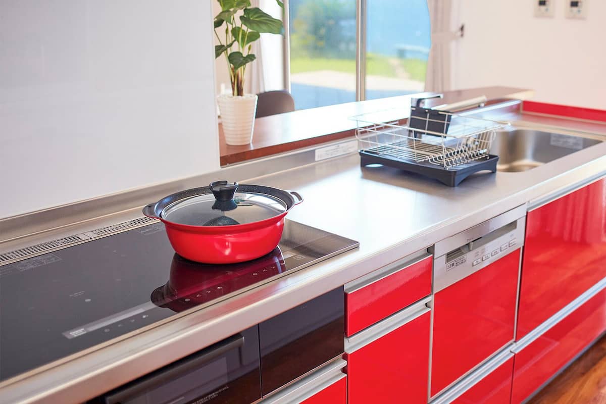 A modern kitchen with a red and black color scheme, a built-in stove, and a dishwasher.