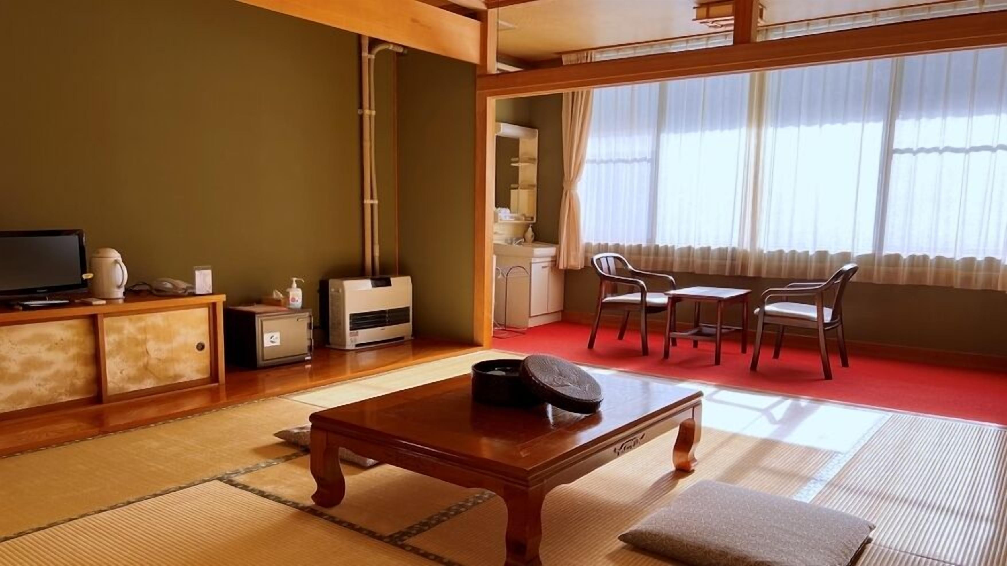 A traditional Japanese-style room with tatami flooring, a low table, a sofa, and a television.