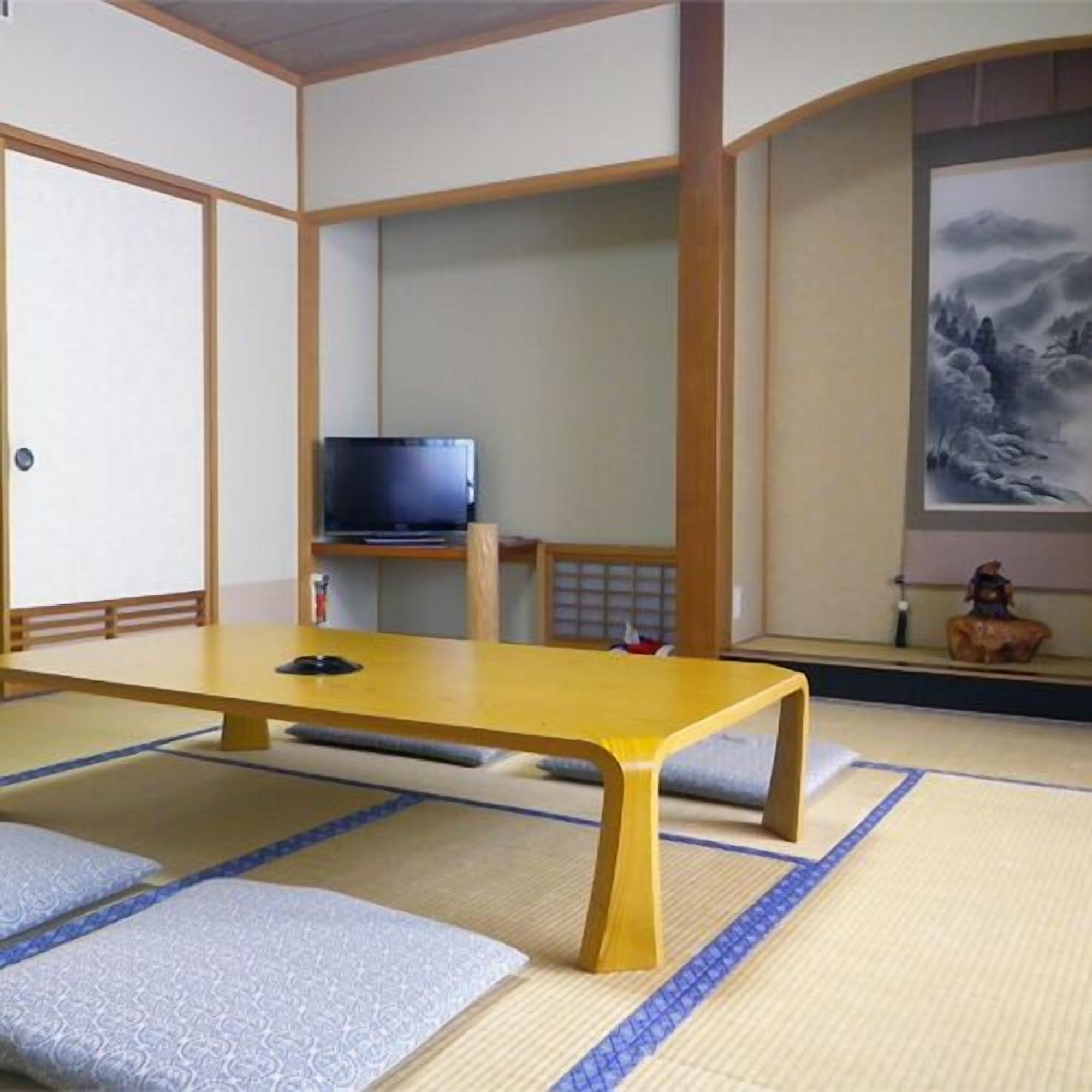 Tatami-mattoilla päällystetty huone, jossa on matala pöytä, televisio ja seinällä taulu.