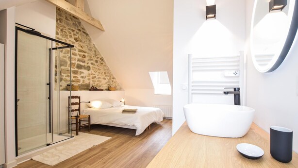 A bedroom with a stone wall, a glass door, a bed, and a chair. - Stunning home in SAINT VAAST LA HOUGUE with WiFi (SAINT VAAST LA HOUGUE)