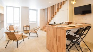 A modern kitchen with a wooden island, black chairs, and a flat-screen TV. - Stunning home in SAINT VAAST LA HOUGUE with WiFi (SAINT VAAST LA HOUGUE)