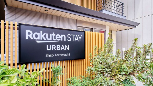 Une enseigne pour Rakuten Stay Urban, avec une façade moderne et des lambris en bois verticaux.