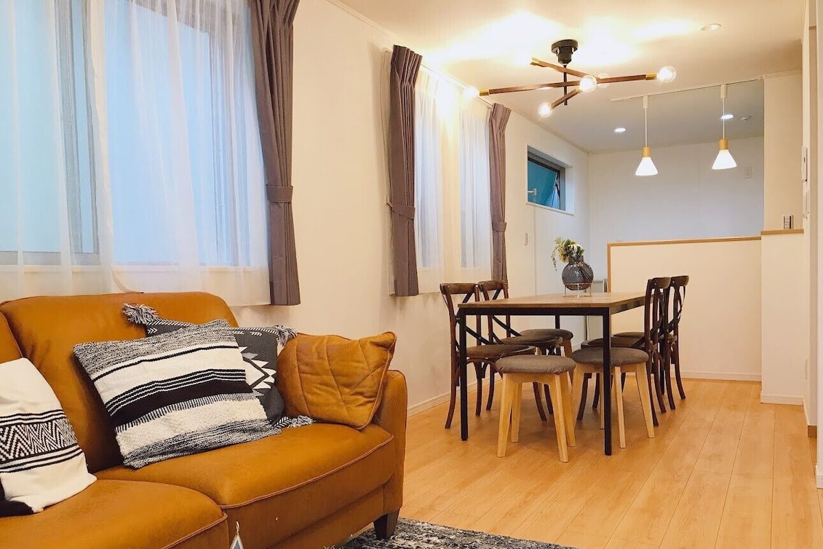 A living room with a sofa, pillows, a coffee table, and a dining area with a table and chairs.