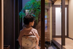 Una persona de pie en un umbral, con vistas a un interior japonés tradicional.