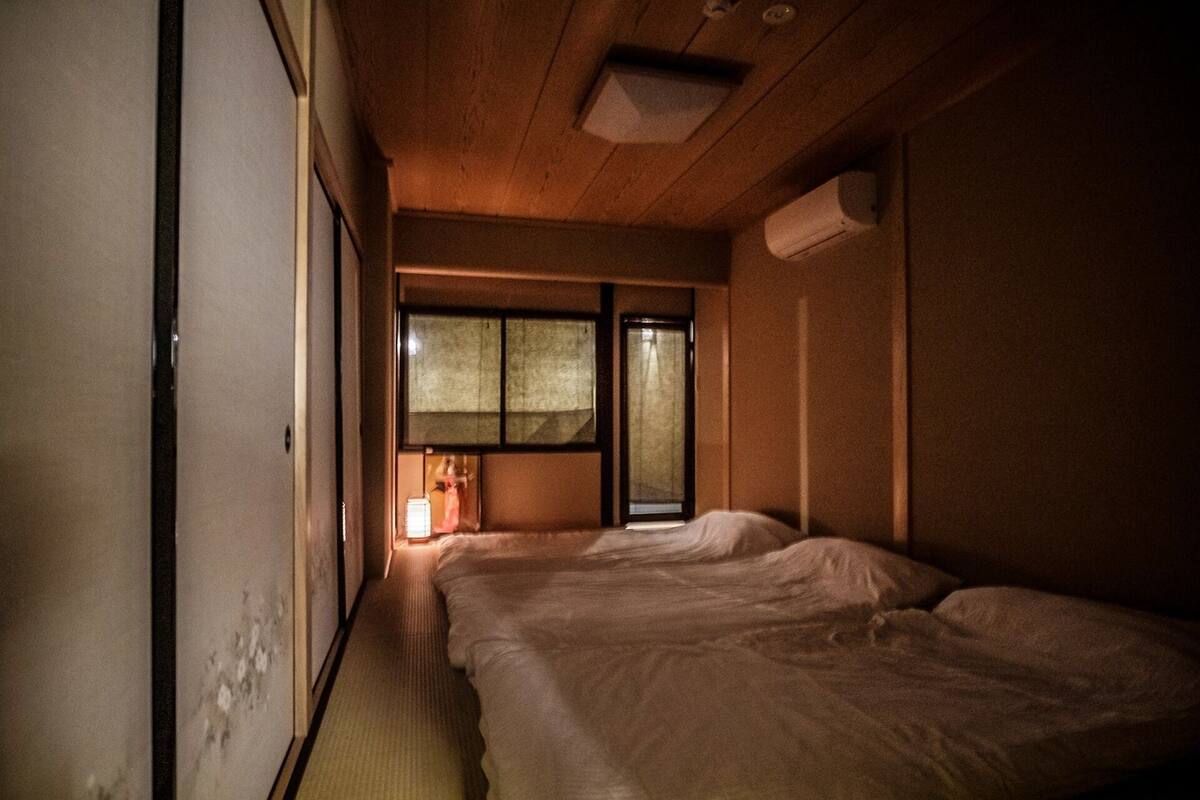 Una habitación con dos camas, una ventana con vistas y un aire acondicionado en la pared.