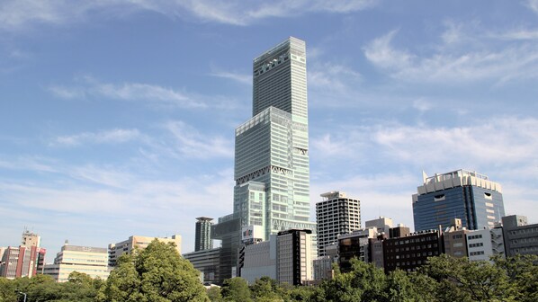 A high-rise building with a modern glass facade, surrounded by other buildings and trees. - Osaka International Center Hotel Uehommachi (Osaka)