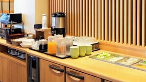 Un buffet de petit-déjeuner d’hôtel proposant une variété d’aliments, de boissons et une machine à café.