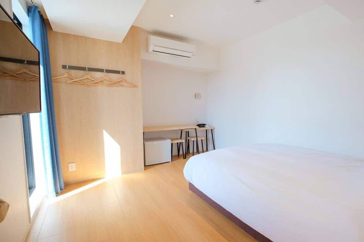 Una habitación de hotel moderna con una cama grande, un escritorio y un armario.