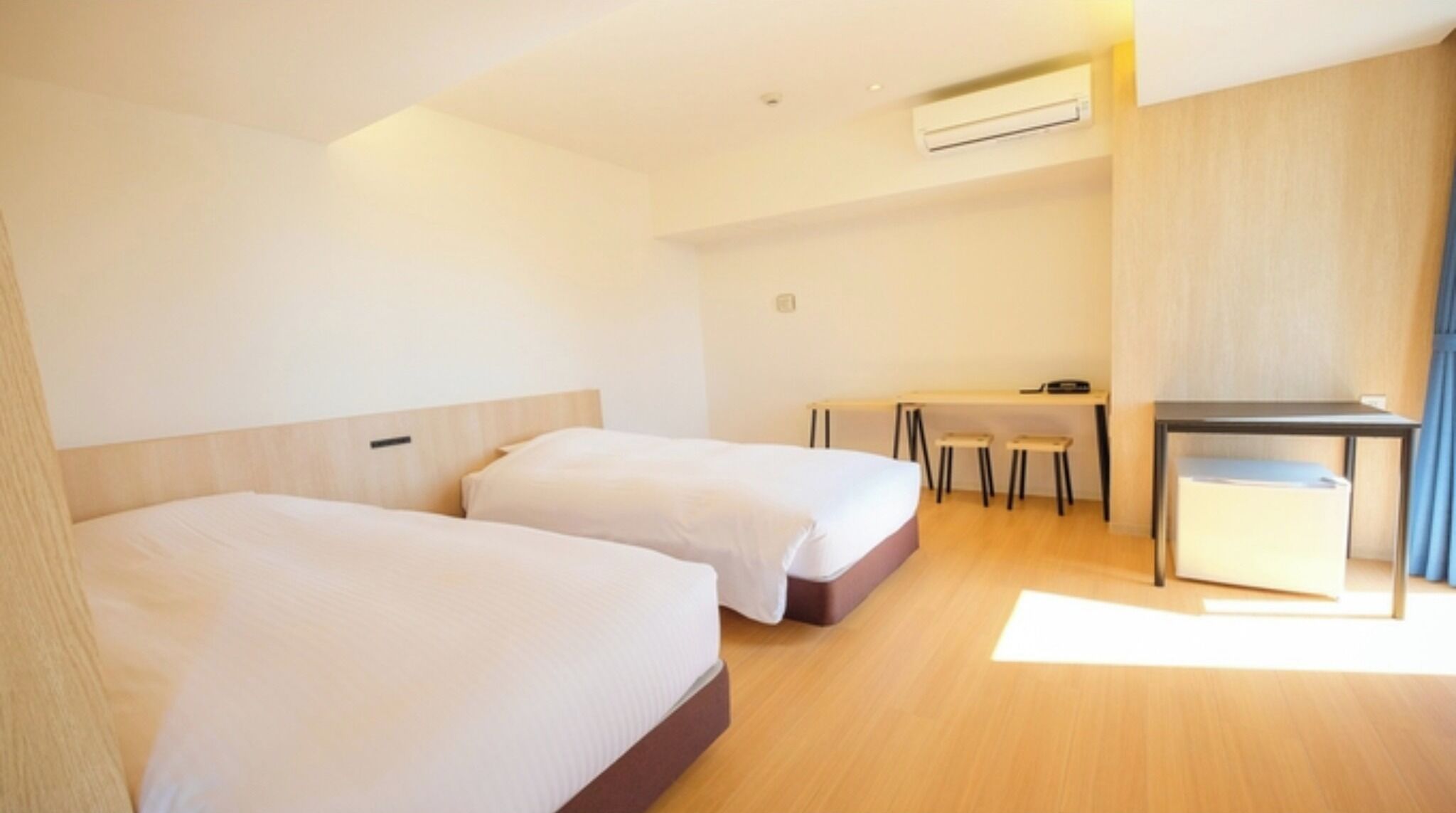 A hotel room with two beds, a desk, and a chair.