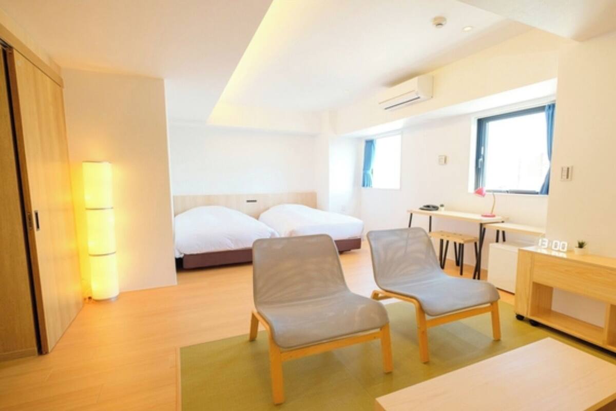 Una habitación de hotel moderna con una cama, dos sillones, un escritorio y una mesita.