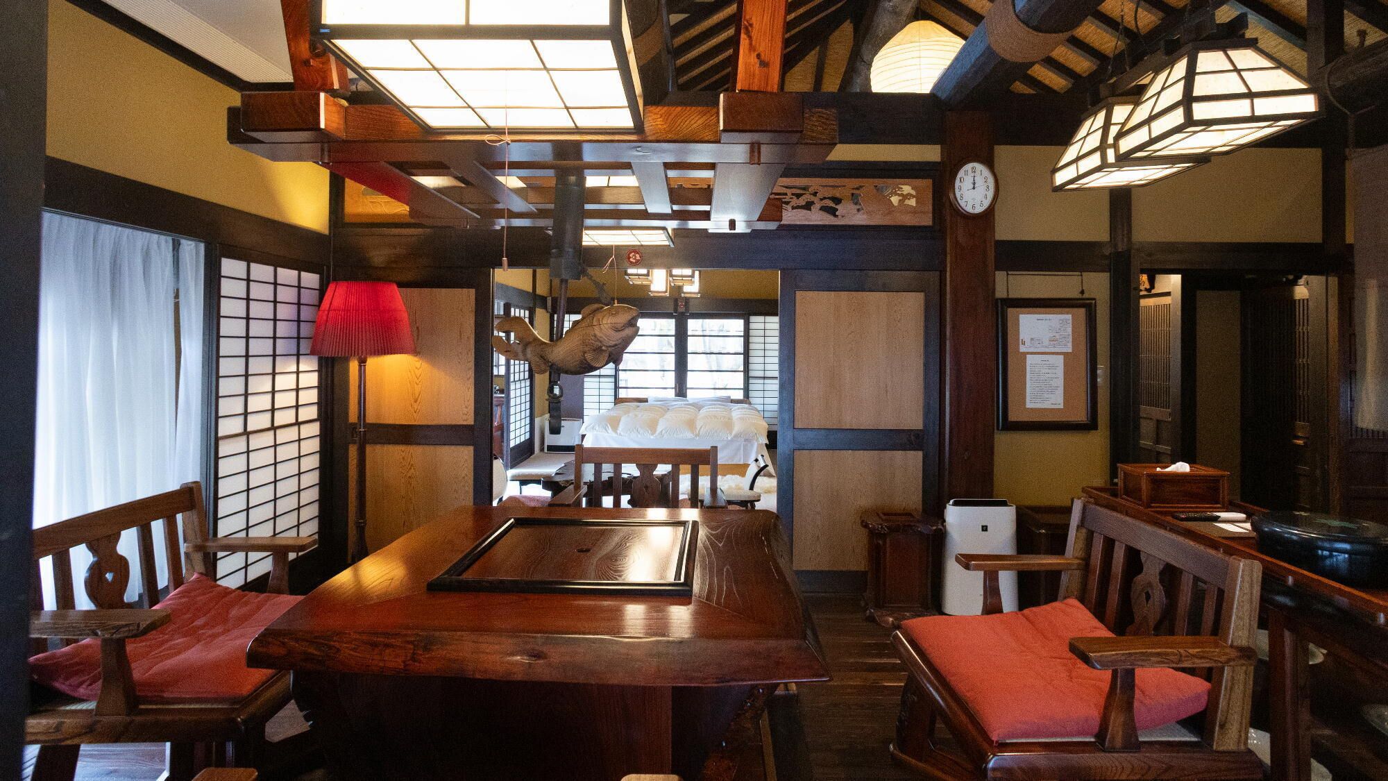 Uma pousada japonesa tradicional com tatames, móveis de madeira e biombos de papel.