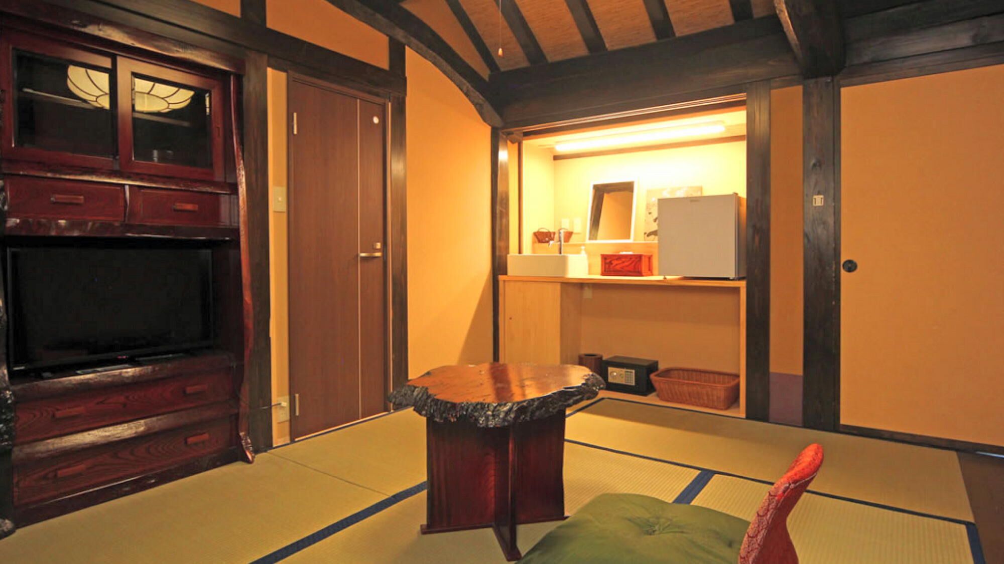 Quarto japonês tradicional com tatames, uma mesa de madeira baixa, uma televisão e um guarda-roupa.
