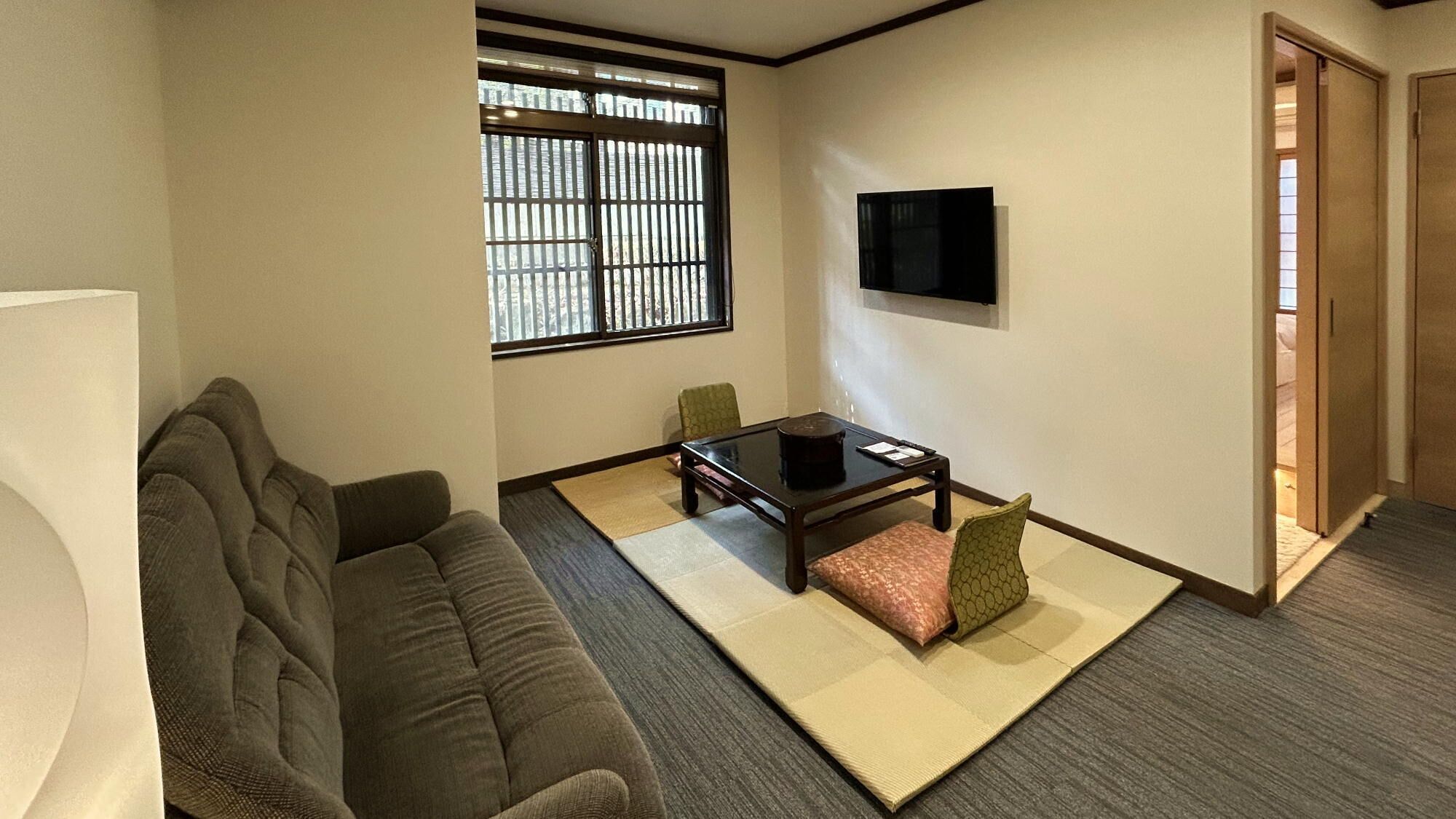 A living room with a sofa, a coffee table, a TV, and a window with blinds.