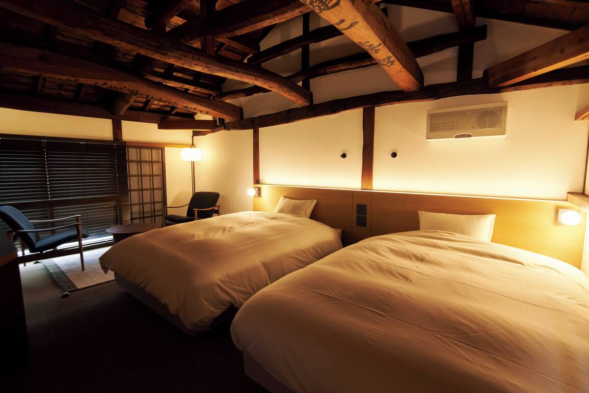Habitación de hotel con dos camas, un escritorio y una silla.