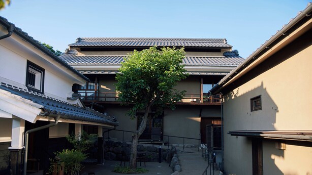 A traditional Japanese building with a tiled roof, a tree in the courtyard, and a stone pathway. - Spa & Hotel La Fontaine Suwa (Ueda)