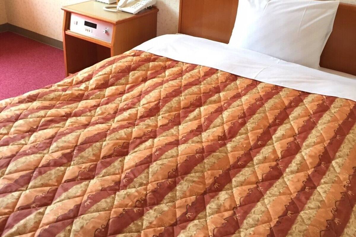 Una habitación de hotel con una cama, una mesita de noche con lámpara y un teléfono.