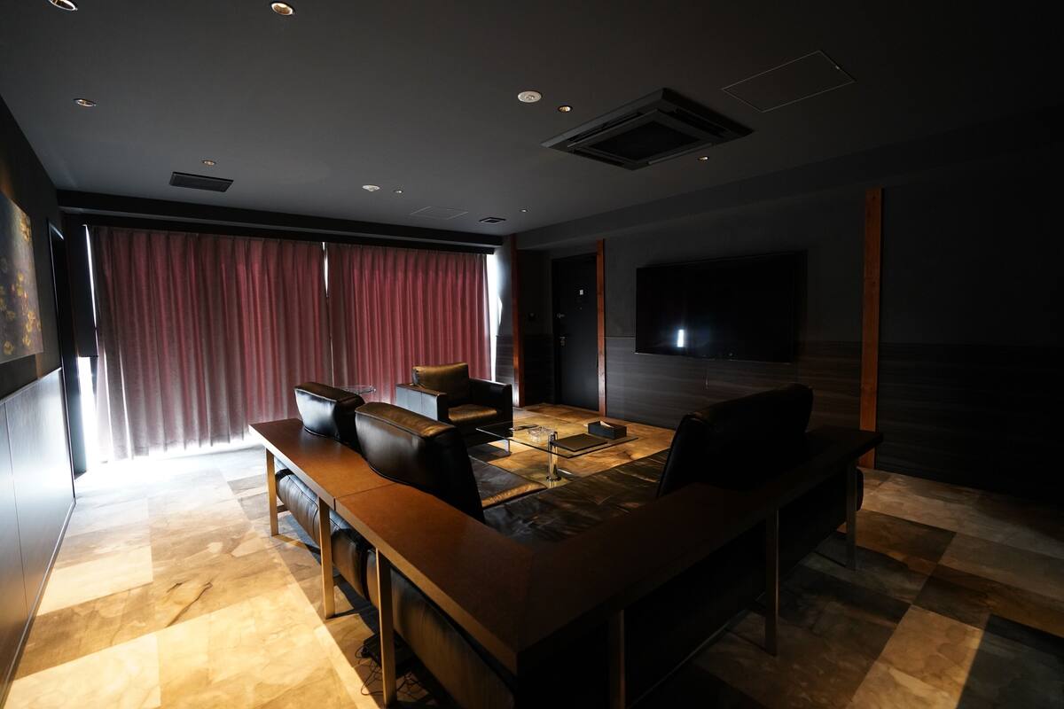 Uma área de refeições moderna com bar, cadeiras de couro e uma grande televisão de tela plana.