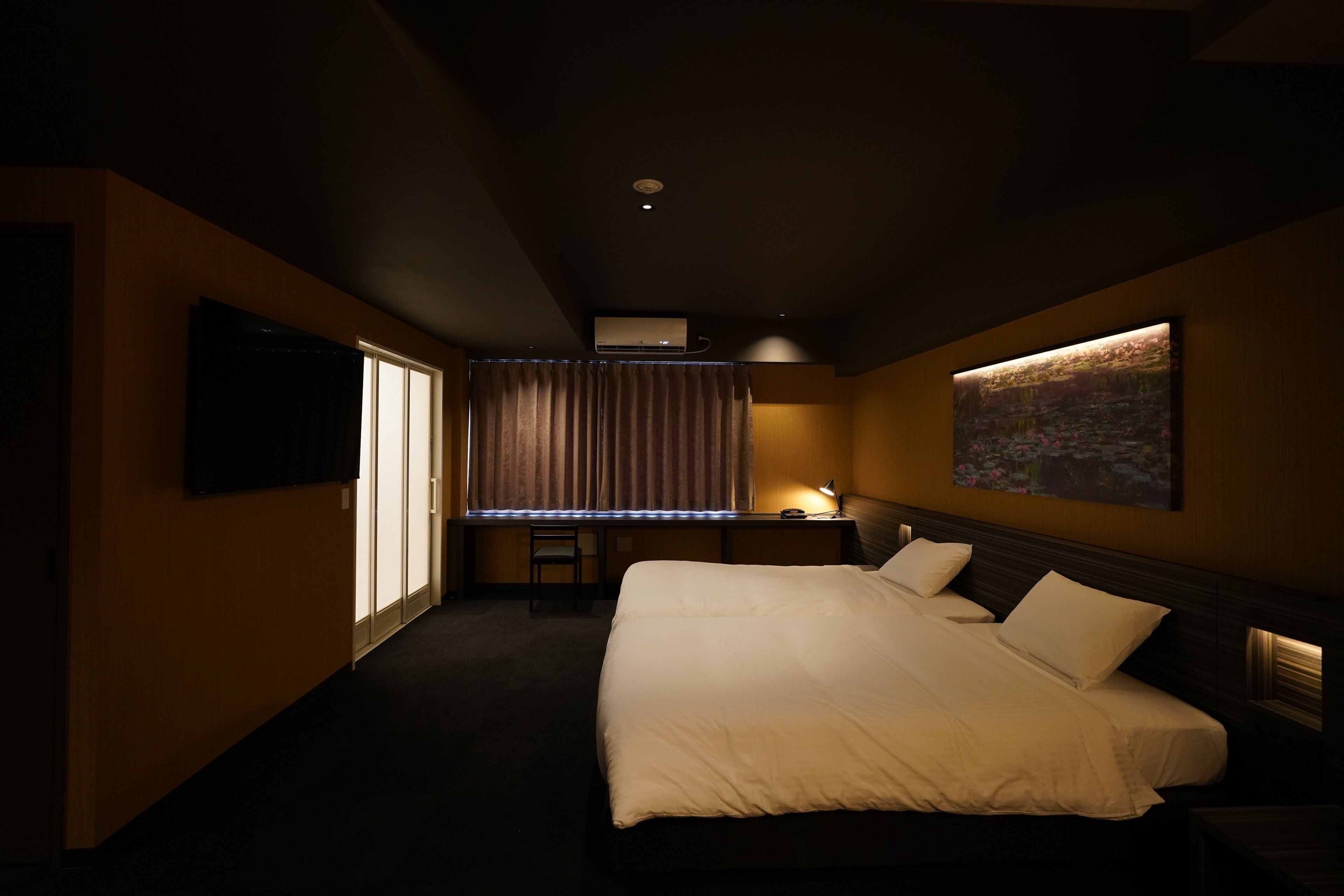 A hotel room with a large bed, a desk, a chair, a TV, and a painting on the wall.