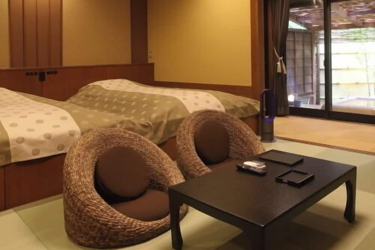 Quarto de hotel com duas camas, uma mesinha e vista para o exterior.
