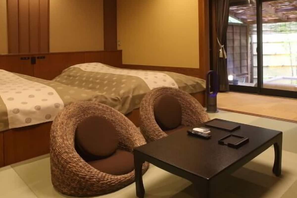 Quarto de hotel com duas camas, uma mesa pequena e vista para o exterior.
