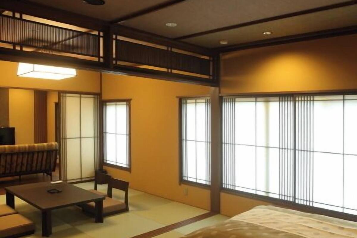 Um quarto japonês tradicional com tatames, uma mesa baixa, um sofá e portas deslizantes shoji.
