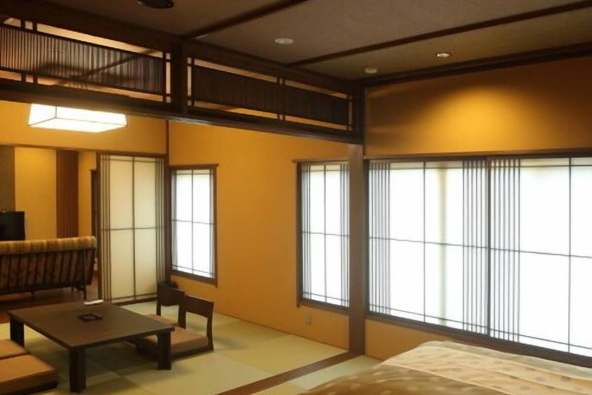 Um quarto japonês tradicional com tatames, uma mesa baixa, um sofá e portas deslizantes.