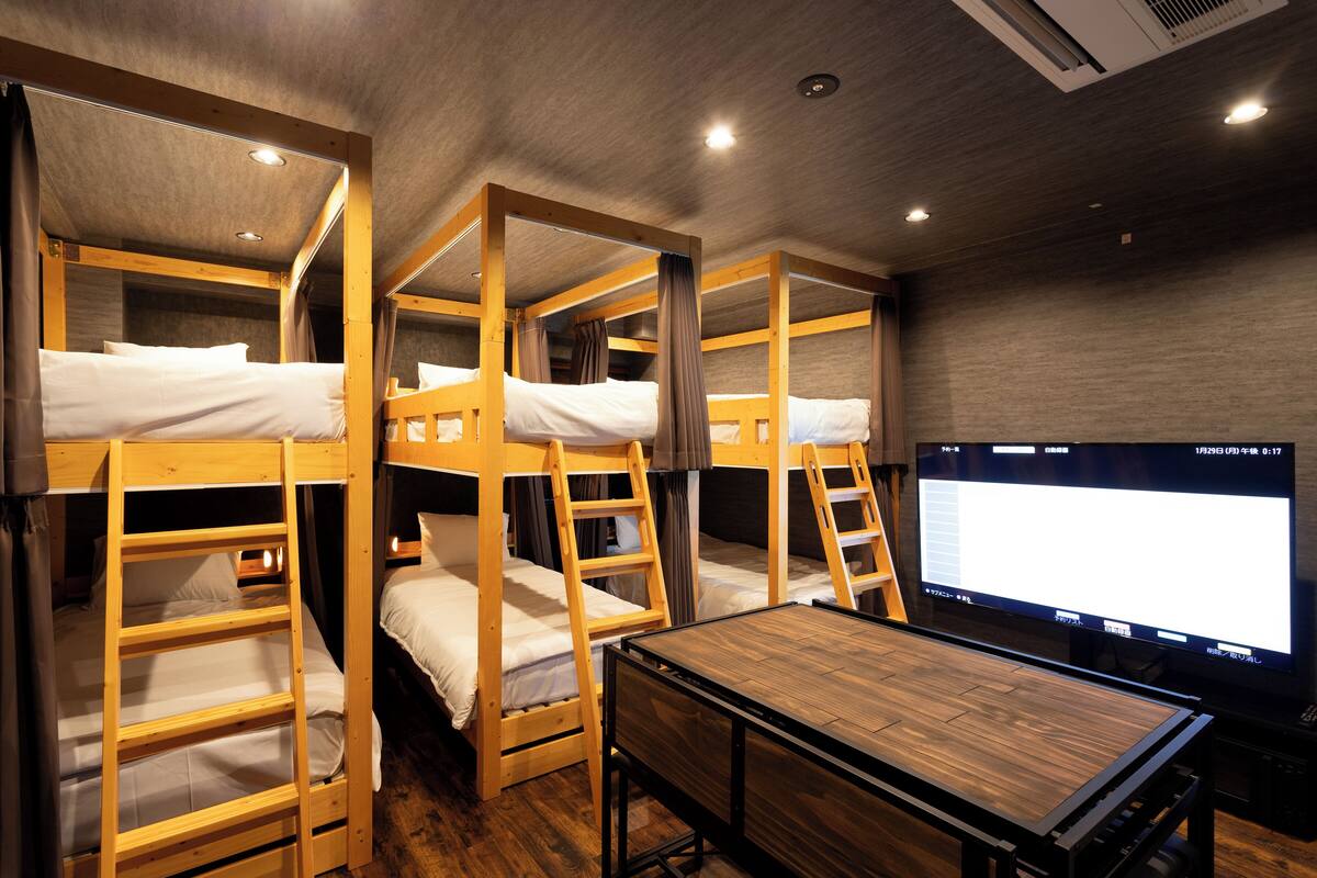 A room with bunk beds, a wooden table, and a television.