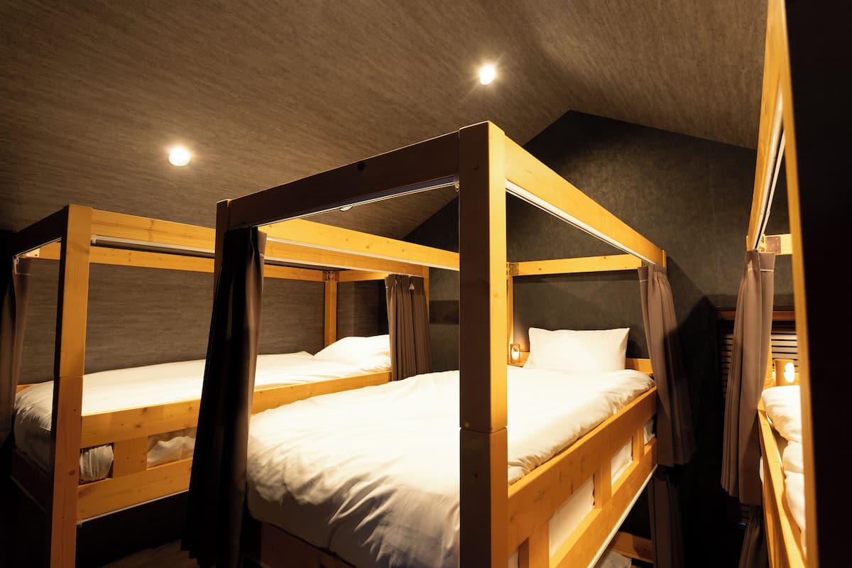 A room with three wooden bunk beds, each with a mattress and pillows.