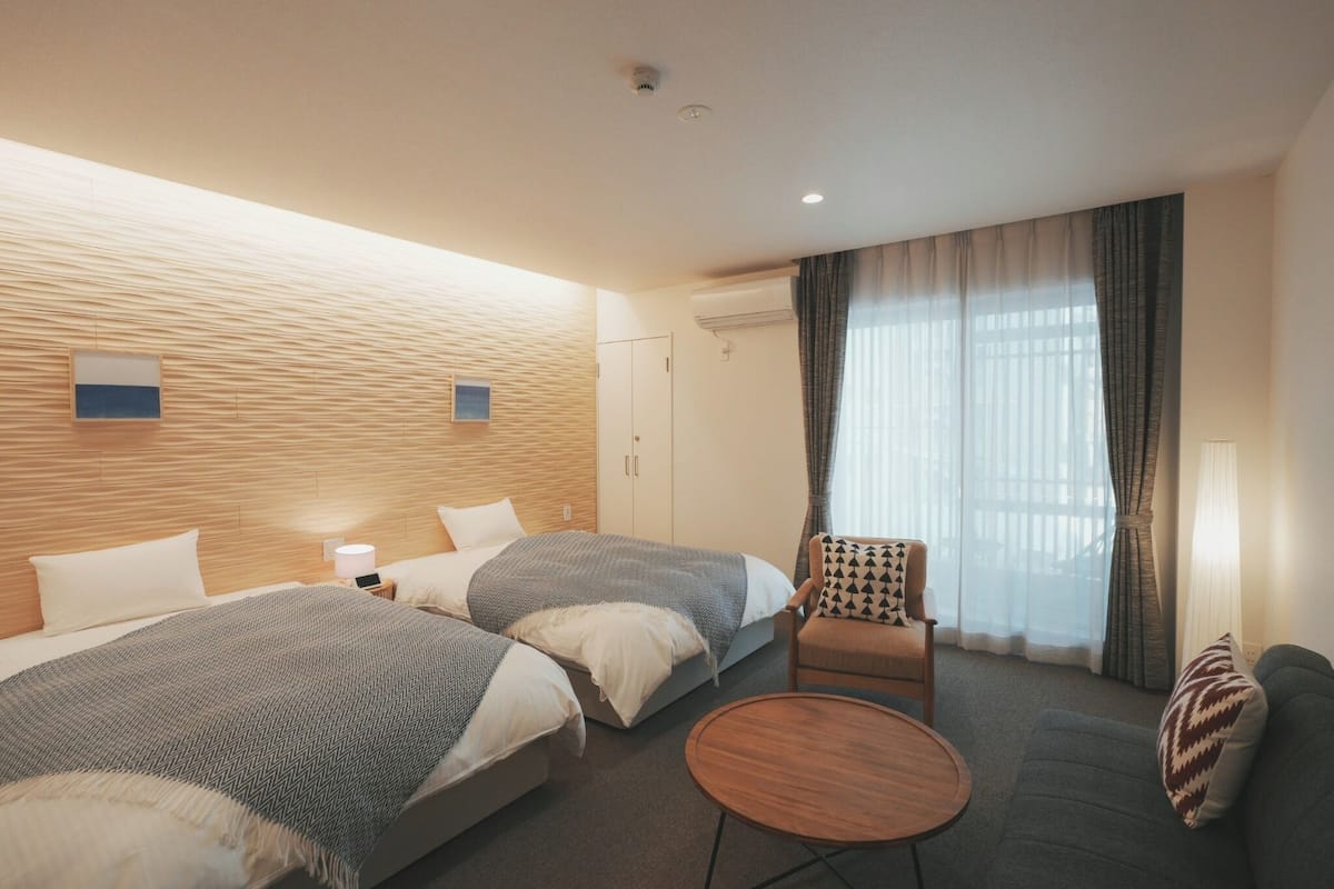 A hotel room with two beds, a sofa, a round table, and a chair.