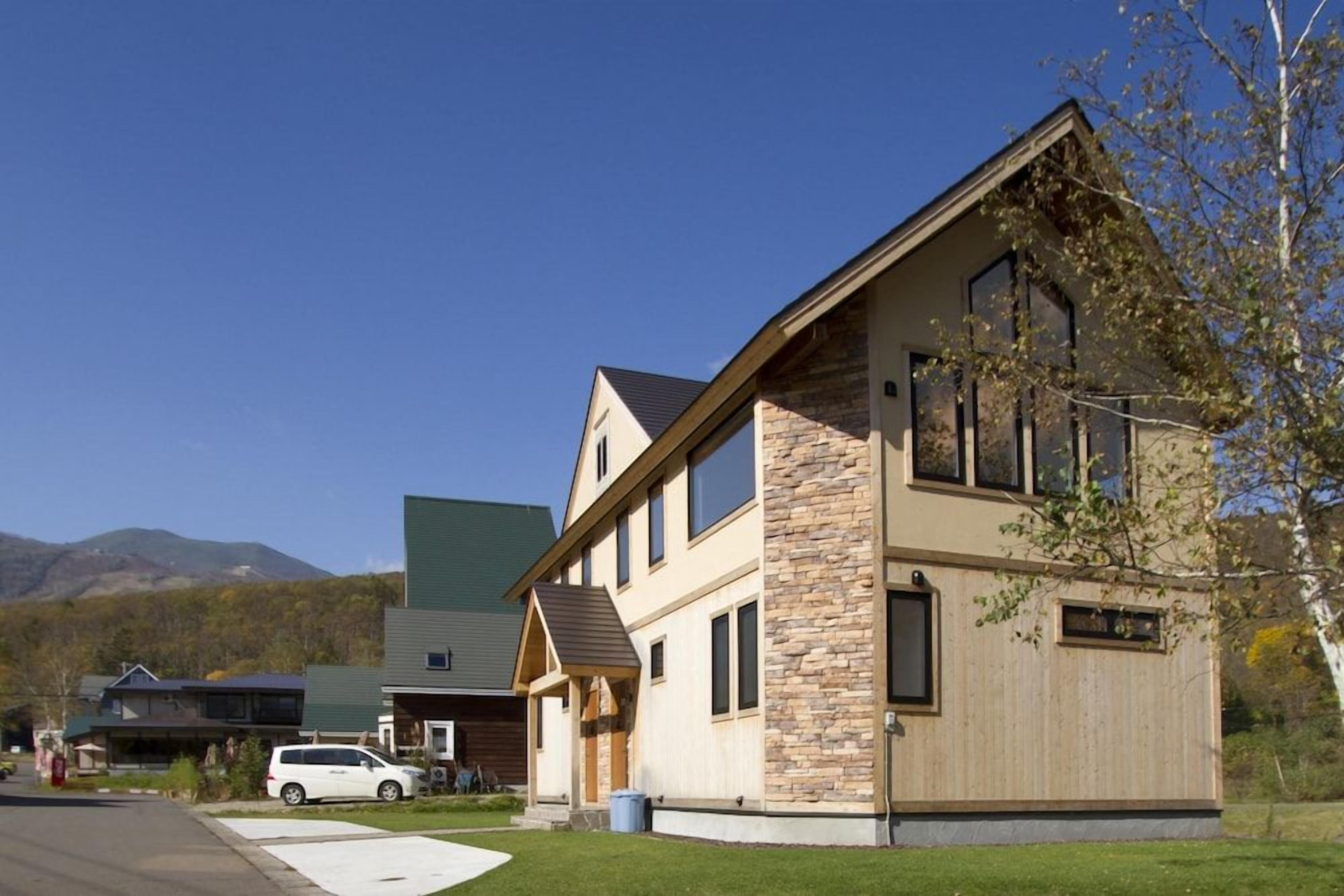 A modern two-story house with a stone facade and a sloped roof.