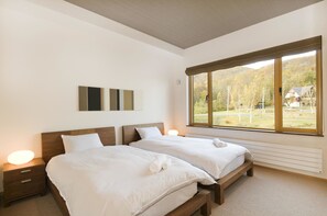A bedroom with two beds, a window with a view of trees, and a wall-mounted artwork. - Hana Jo (Kutchan)