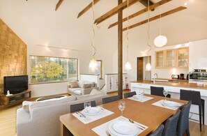 Una sala de estar moderna con un sofá, una mesa de comedor para dos personas y una cocina al fondo.