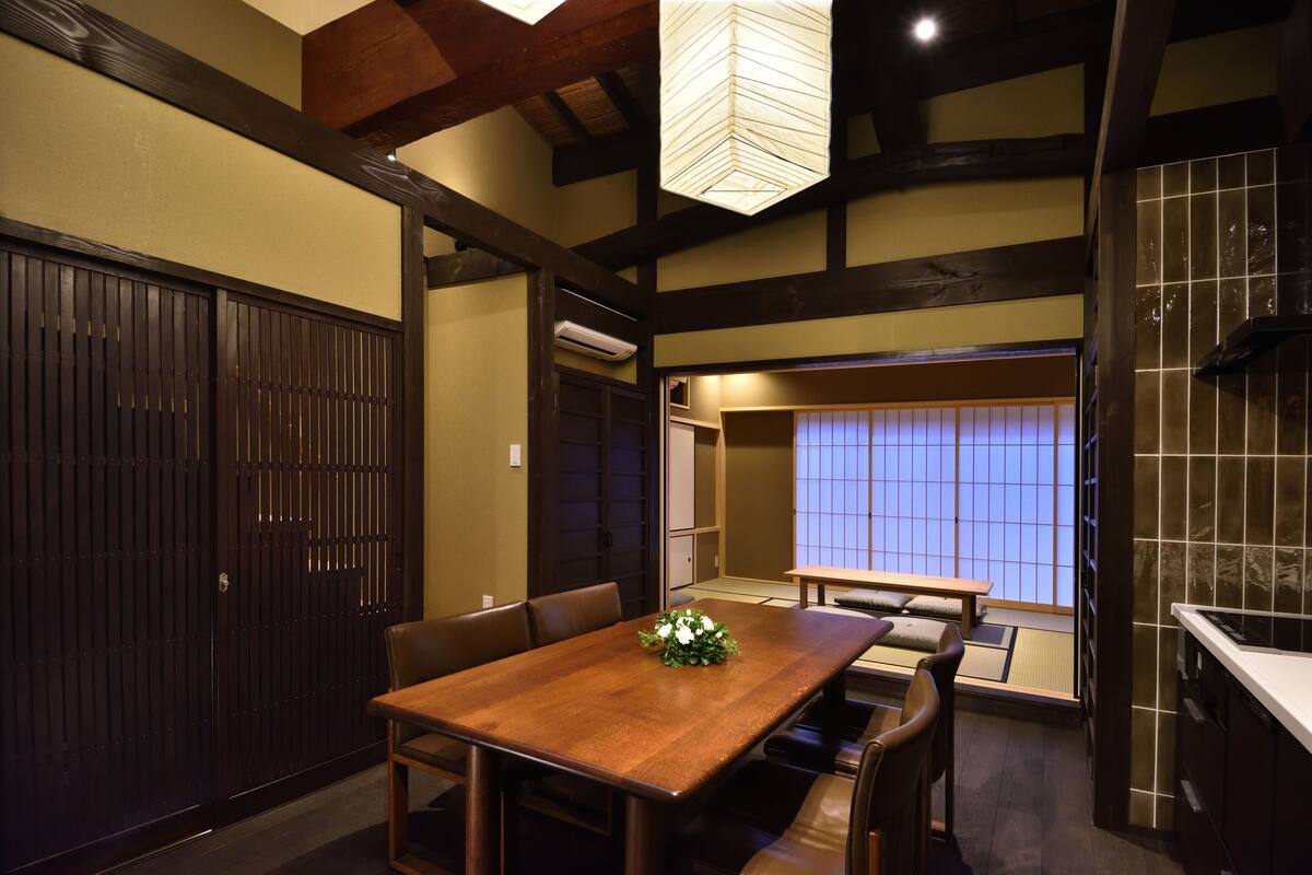 A traditional Japanese-style room with tatami flooring, a wooden dining table, and a sliding door.