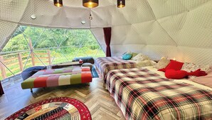 A cozy, well-lit tent with a bed, two smaller beds, a patterned rug, and hanging lights. - Nora (Hokuto)