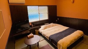 A room with a bed, a TV, a small table, and a window with a view. - Nora (Hokuto)