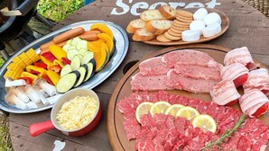 A wooden table with various food items including sliced vegetables, meats, and bread. - Nora (Hokuto)