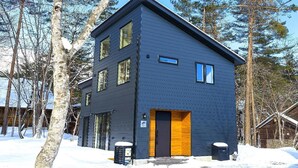 A modern two-story building with large windows and a dark exterior, surrounded by trees and snow. - Spa & Hotel La Fontaine Suwa (Ueda)