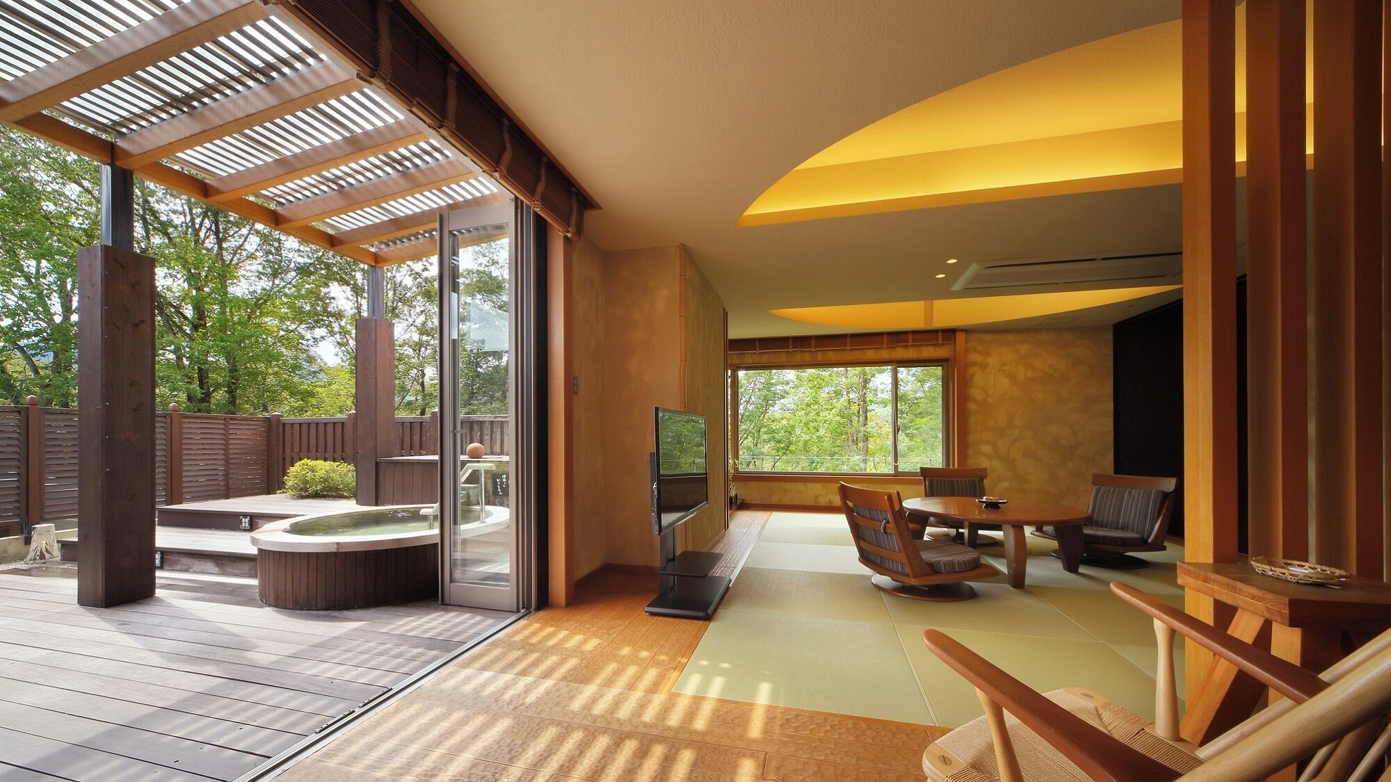 A modern interior with a wooden deck, a hot tub, and a dining area with tatami mats.