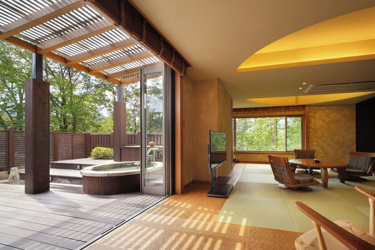 Un interior moderno con terraza de madera, un jacuzzi y un comedor con esteras de tatami.