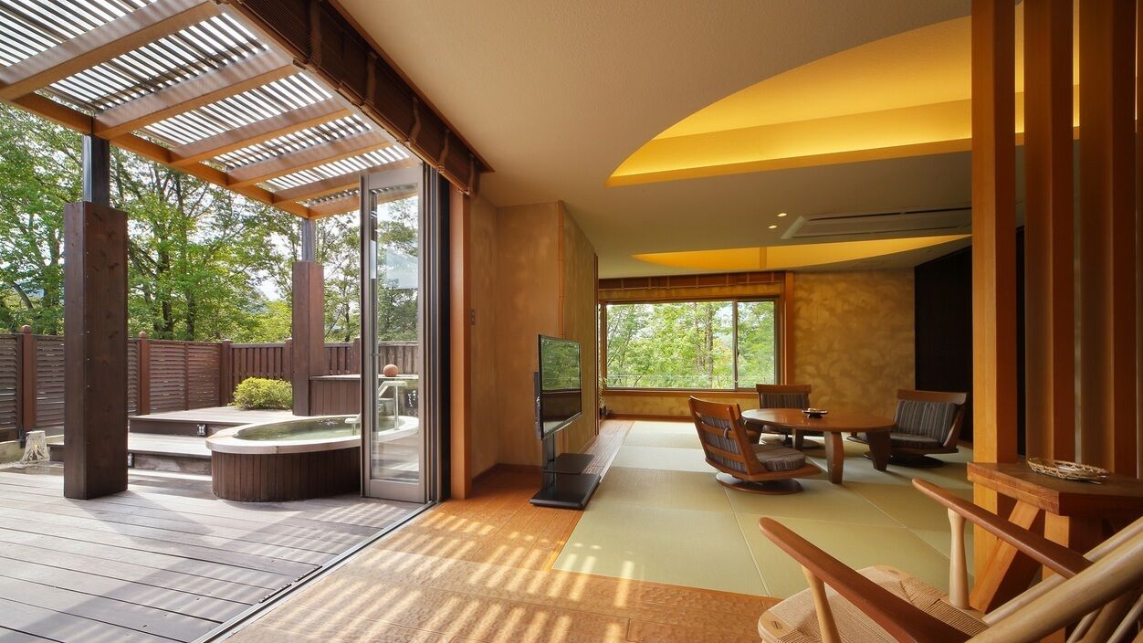 Un interior moderno con una terraza de madera, un jacuzzi y una zona de estar con televisor.
