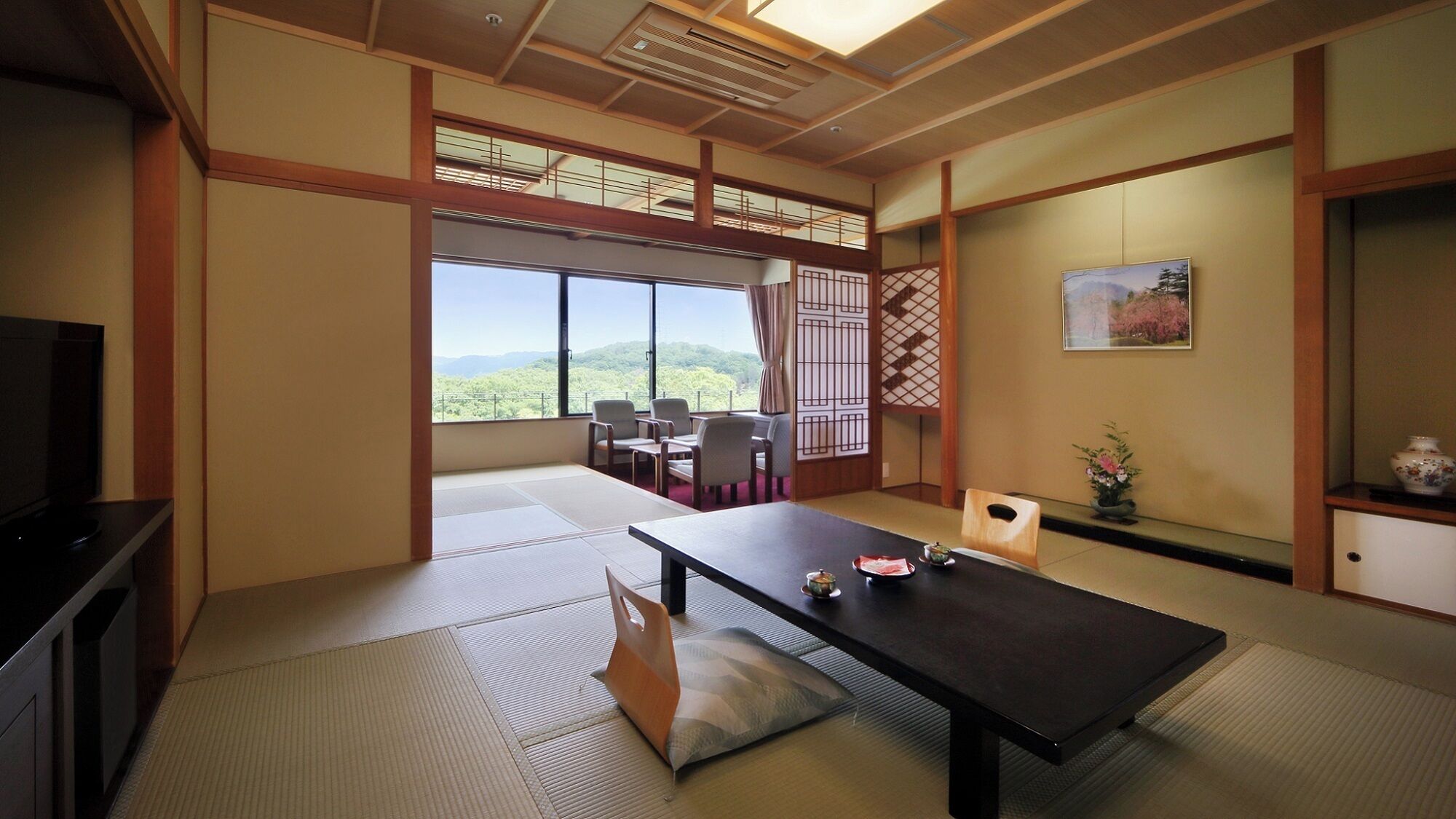 A traditional Japanese room with tatami flooring, a low table, and a view of the mountains.