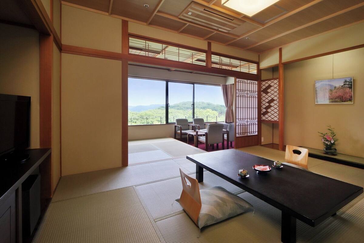 Una habitación japonesa tradicional con suelo de tatami, una mesa baja y vistas a la montaña.