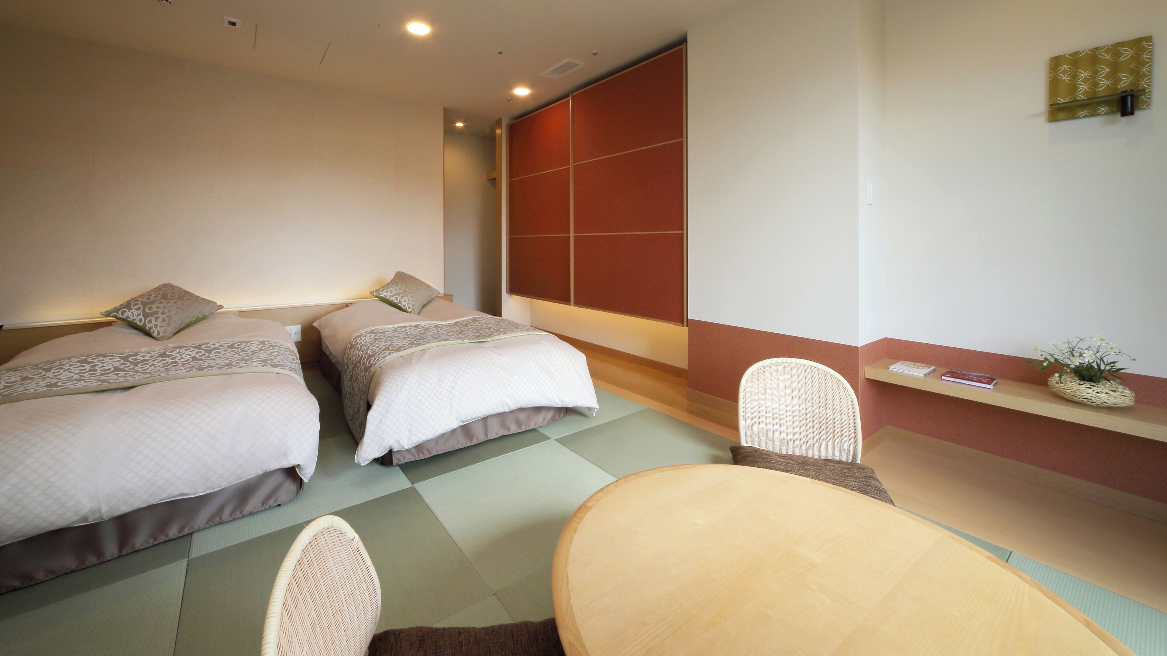 A hotel room with two beds, a small table, and a chair.