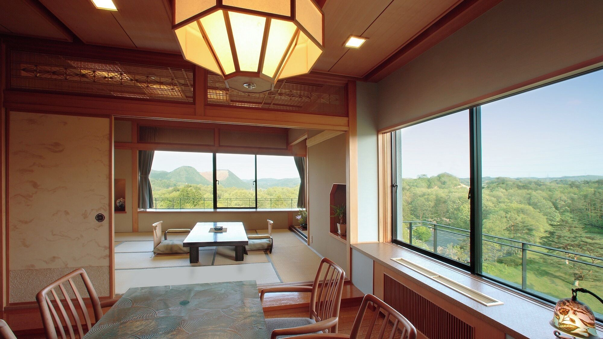 A room with a large window, a dining table, chairs, a sofa, and a traditional Japanese lantern.