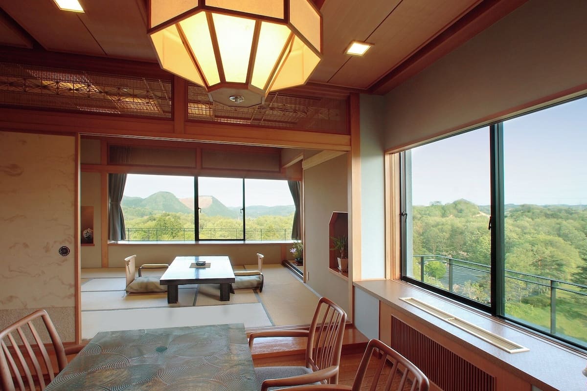 Una habitación con un ventanal grande, una mesa de comedor, sillas, un sofá y un farol japonés tradicional.