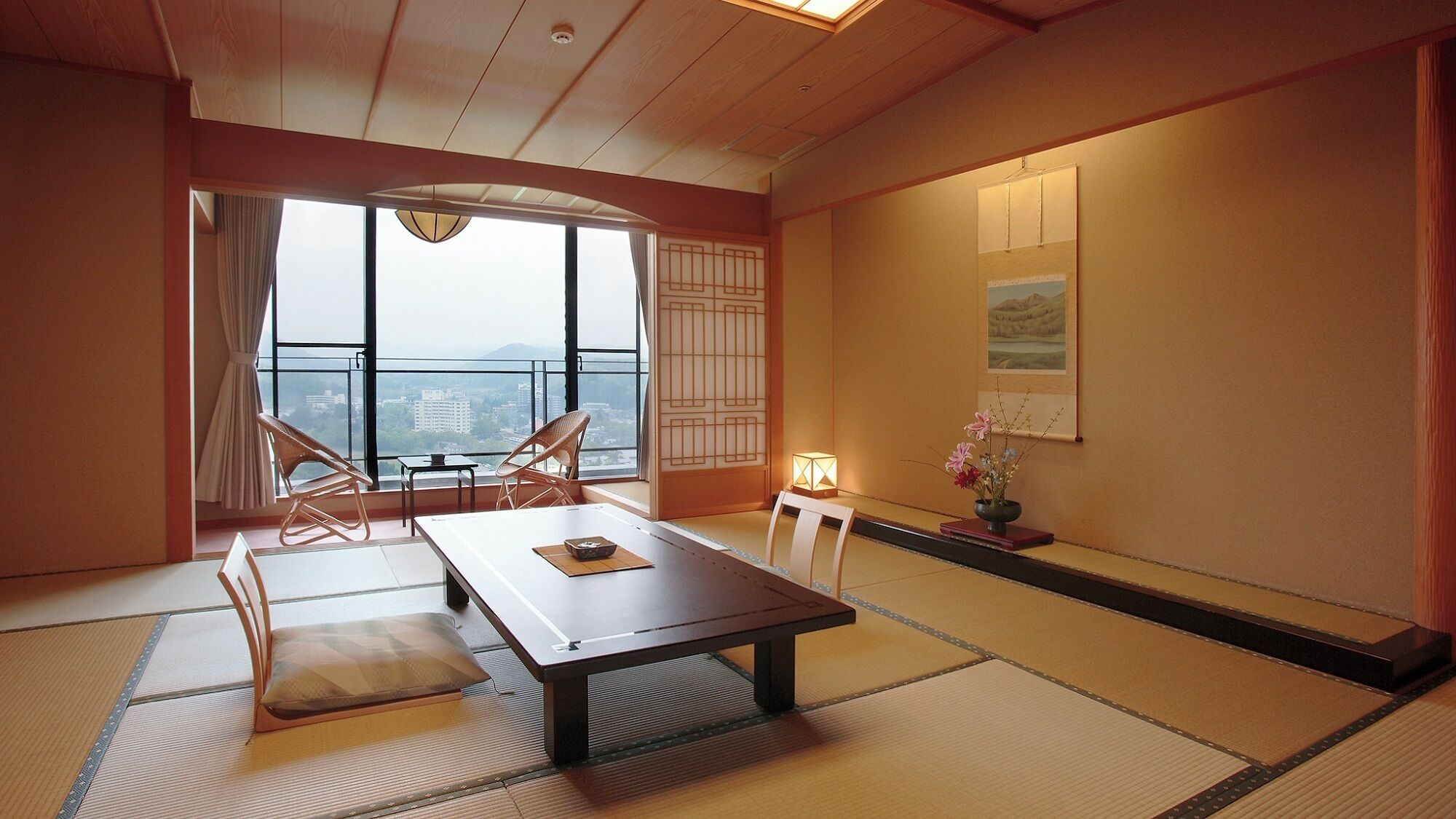A traditional Japanese room with tatami flooring, a low table, and a view of a cityscape through large windows.